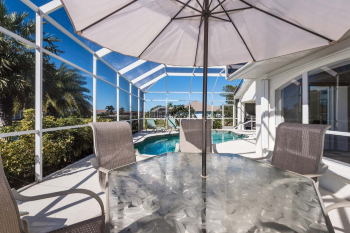 Dining alfresco under the parasol, with views over the pool and canal